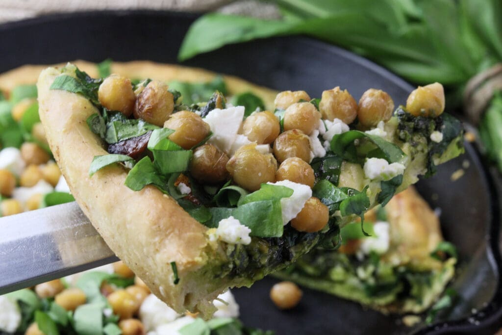 image showing a slice of delicious wild garlic pizza with chickpeas
